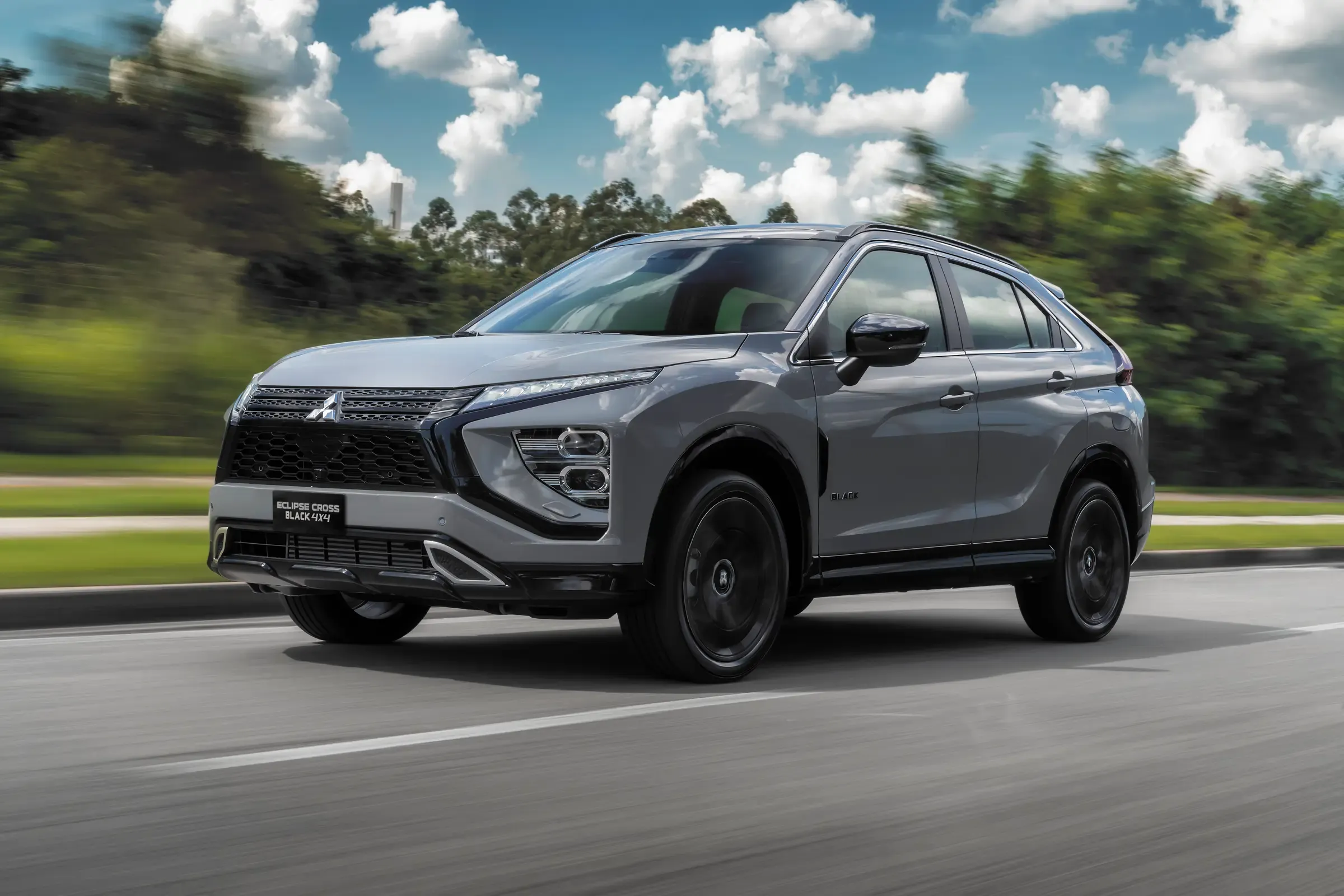 Eclipse Cross prata em movimento numa estrada entre árvores