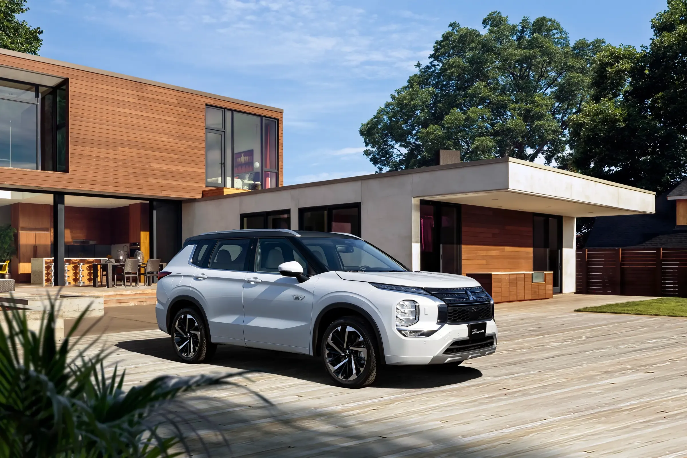 Outlander branco estacionado diante de uma casa de madeira