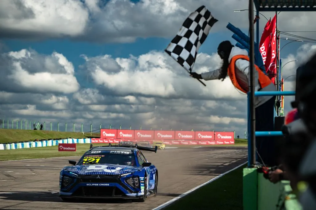 Carro de corrida azul com a carroceria do Eclipse Cross no autódromo, com a bandeira quadriculada ao fundo